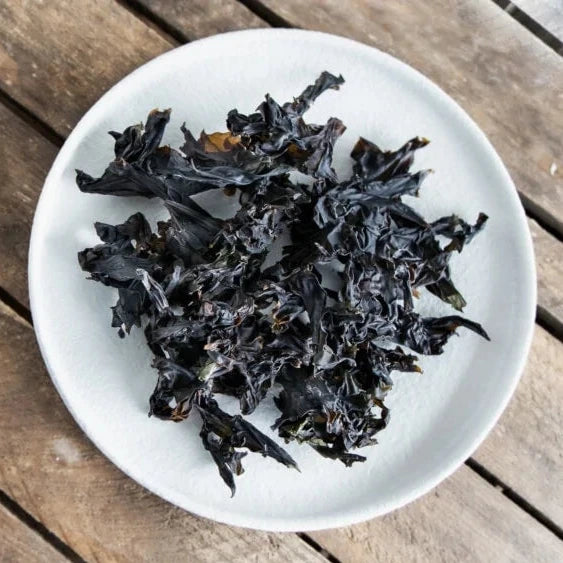 Dried seaweed on a white plate on a wooden surface