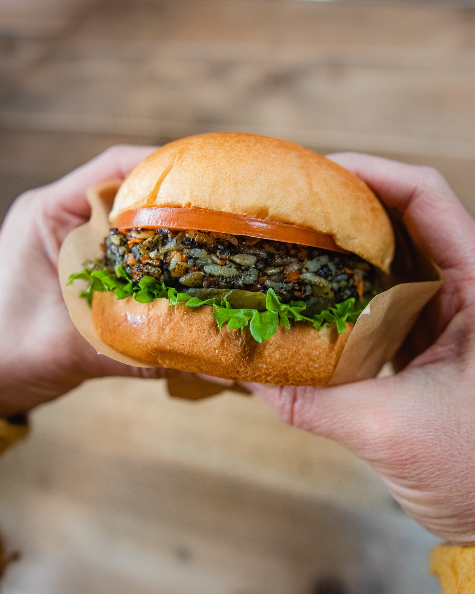 two hands holding a vegetarian rice burger with seaweed