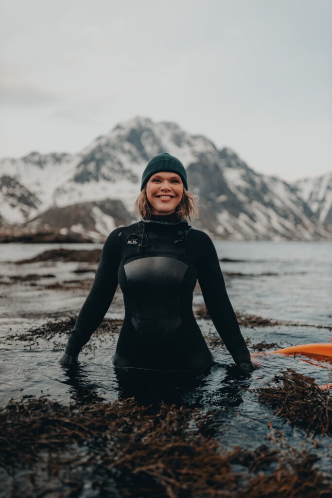 smiling woman in wetsuit standing in the ocean