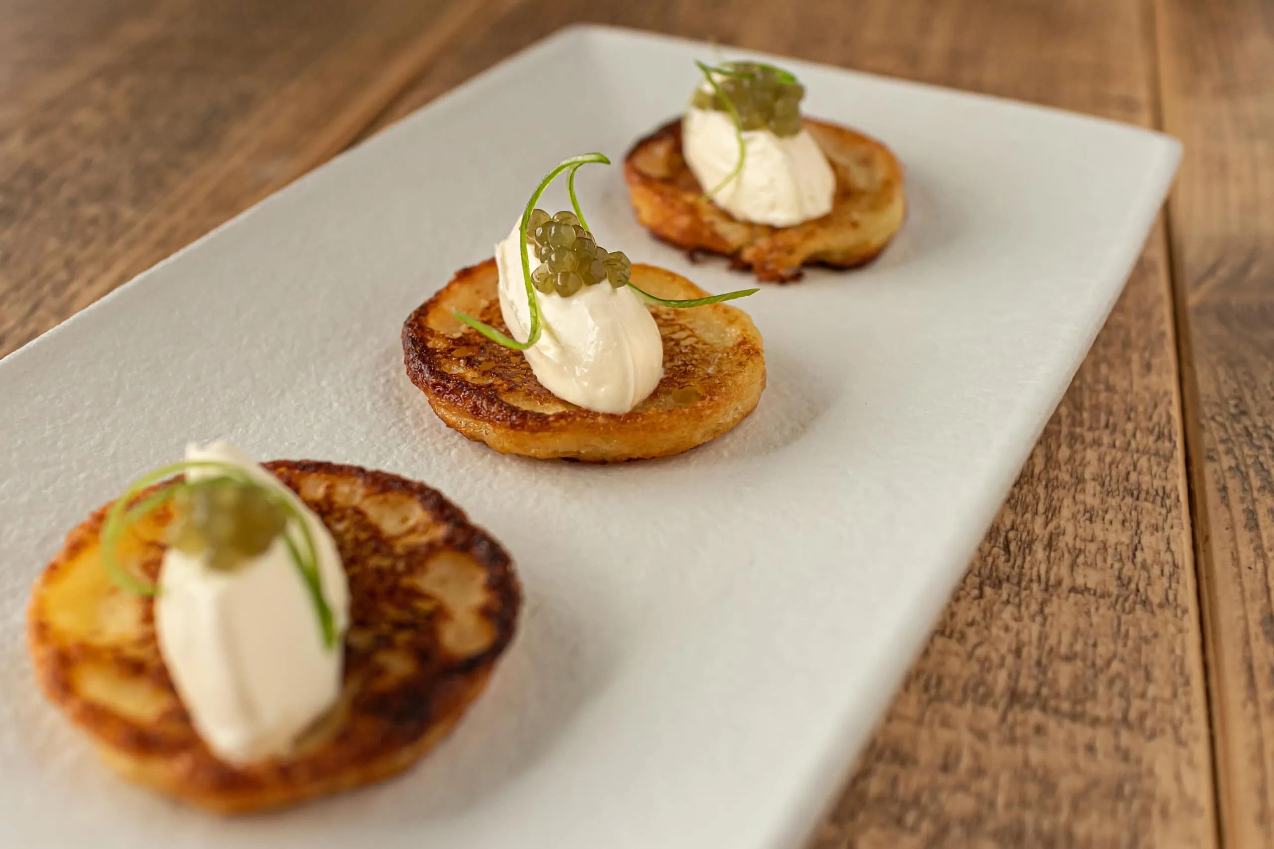 Potato blinis with sour cream and algae pearls