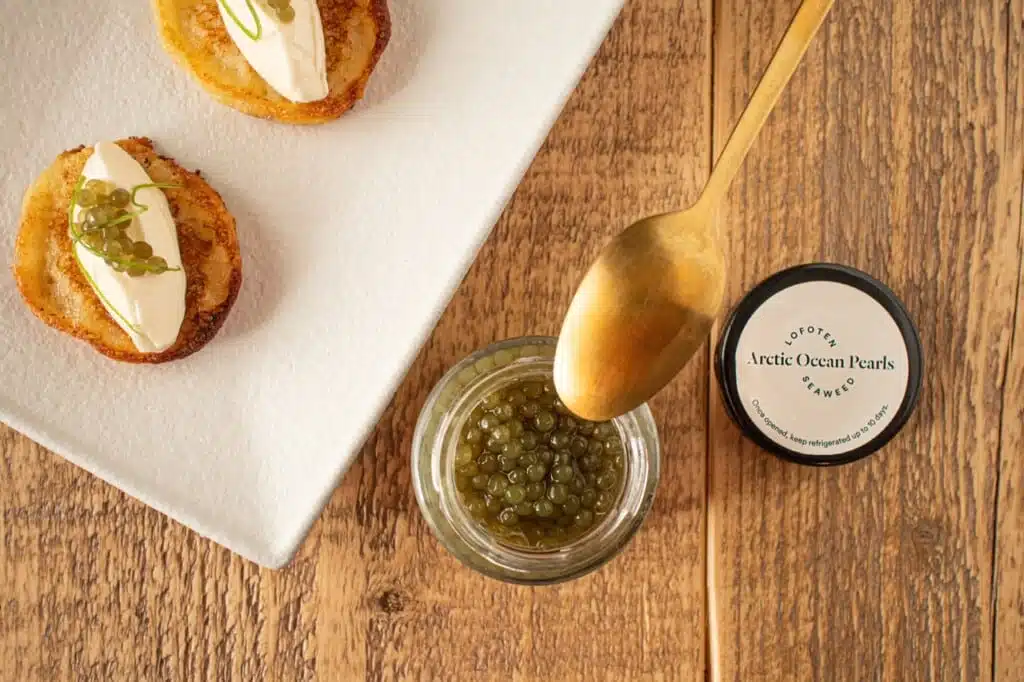 algae pearls on potato blinis with a gold spoon